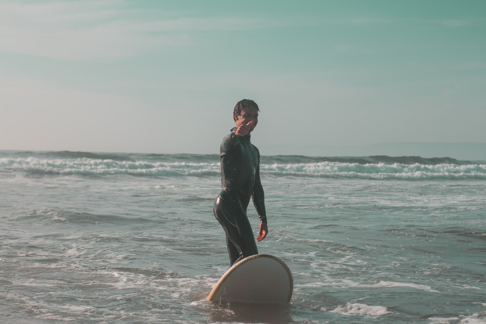 Surfer in wetsuit standing with surfboard in ocean waves