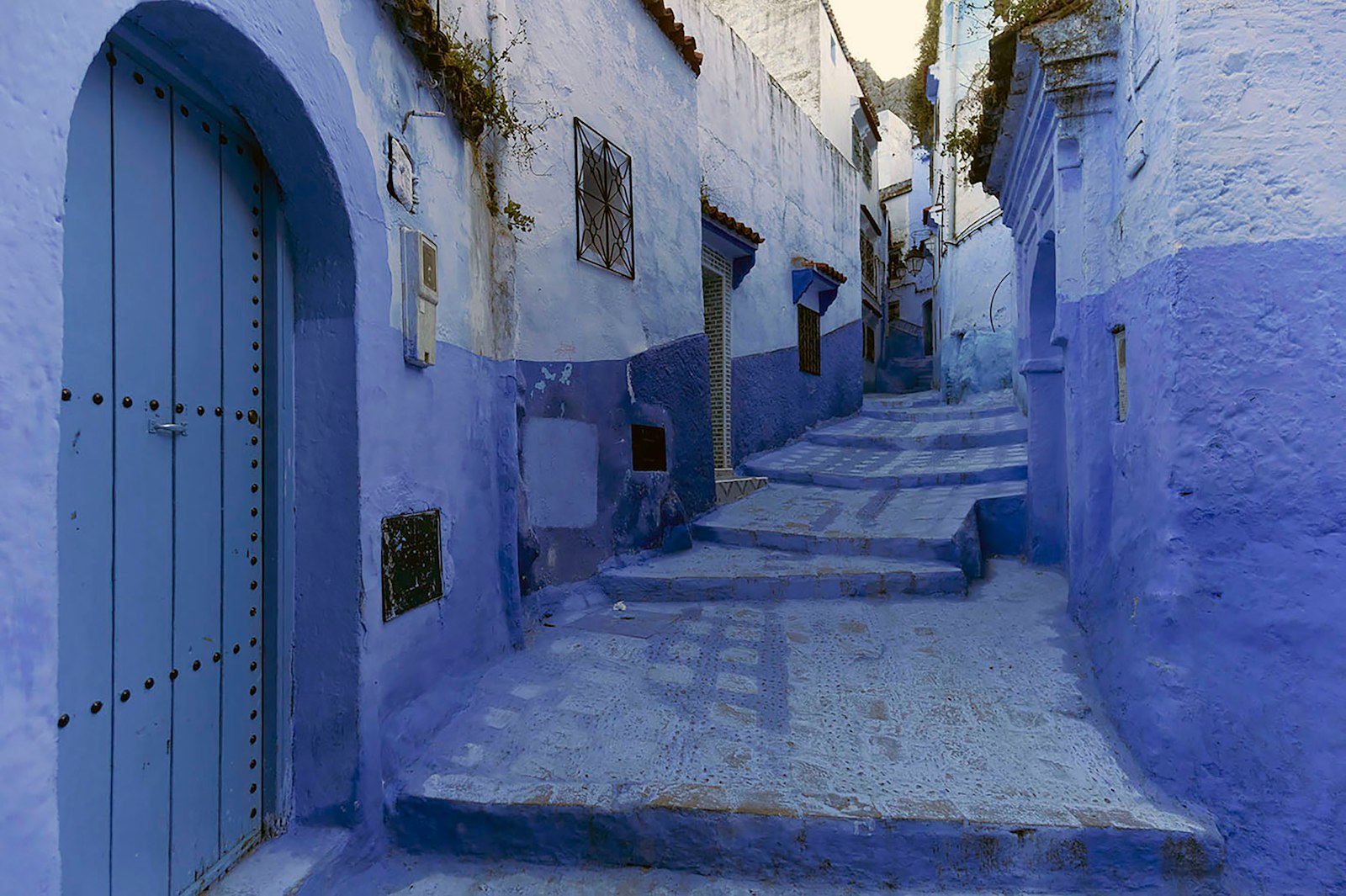 Blue alleyway with stairs and a blue door.