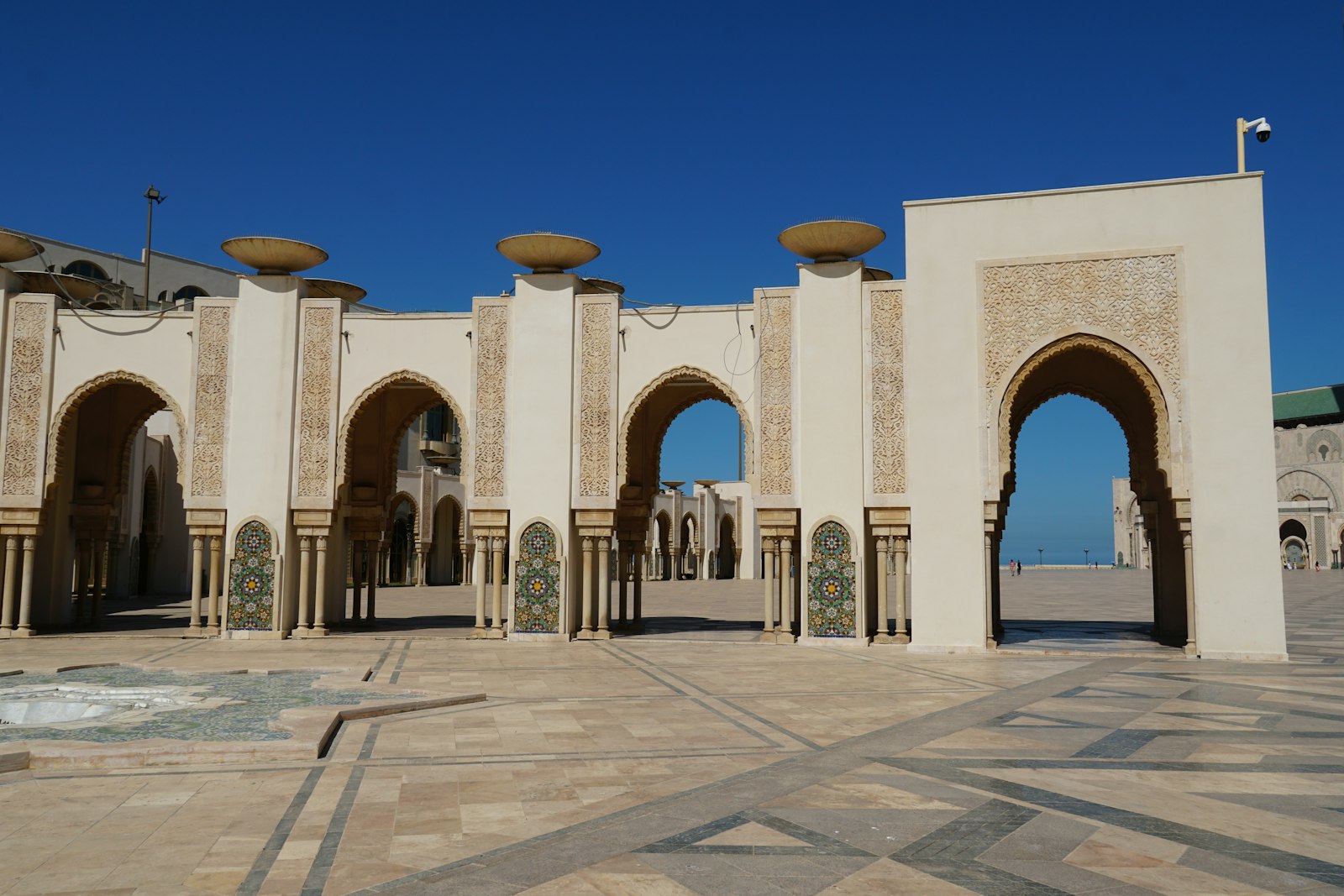 Arches and courtyard of a mosque under blue sky.