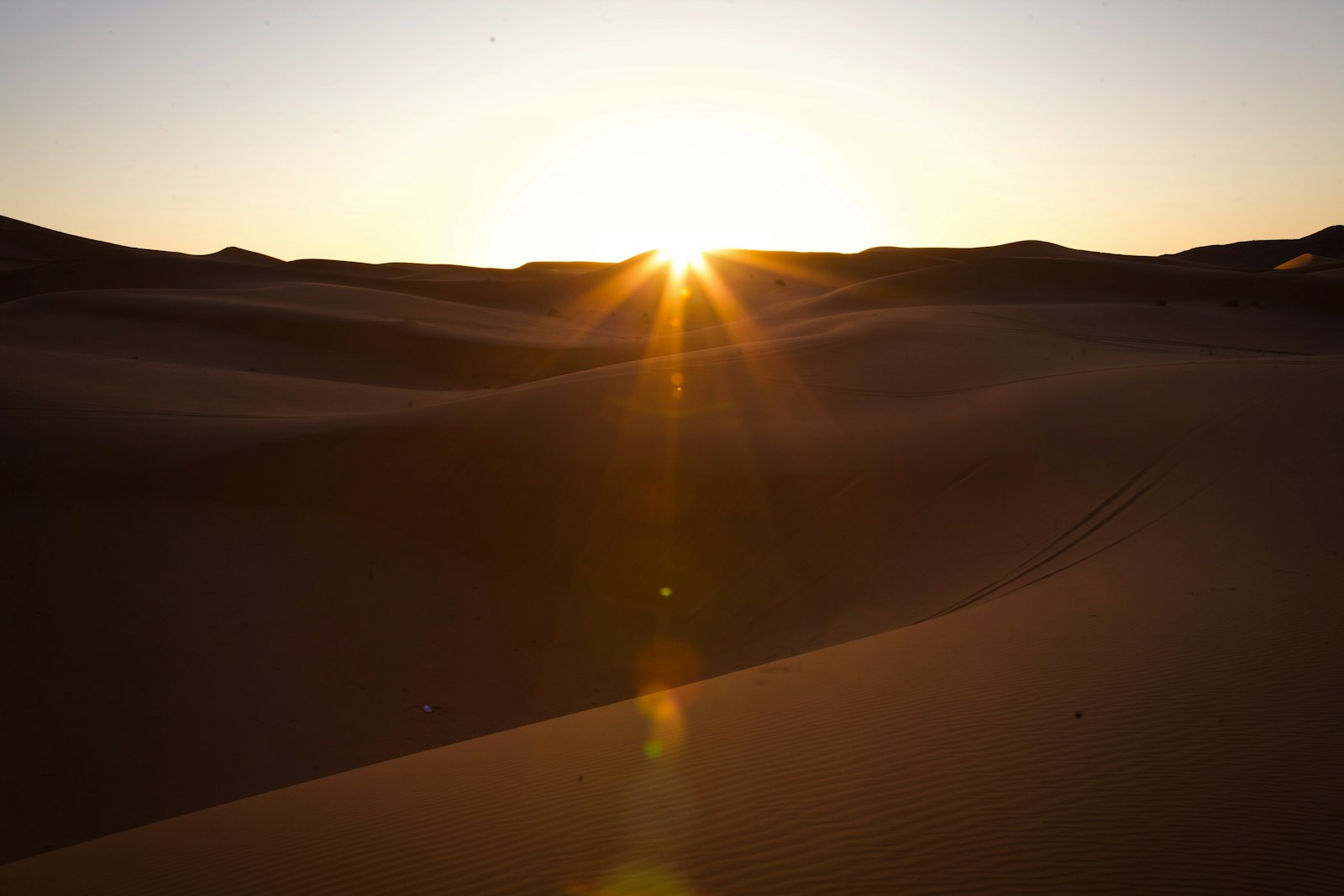 the sun is setting over the sand dunes