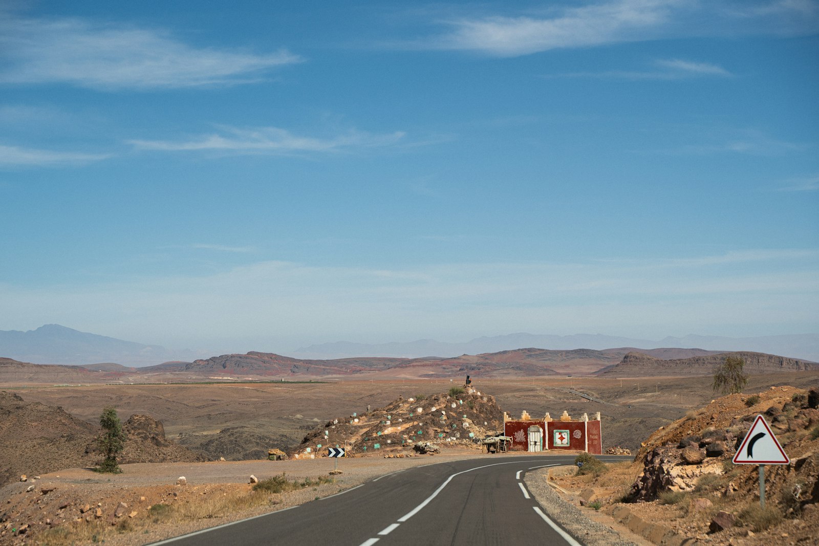 Winding road through arid desert landscape with red building