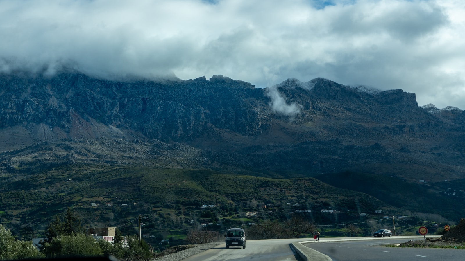 Cars on a road with mountains and clouds