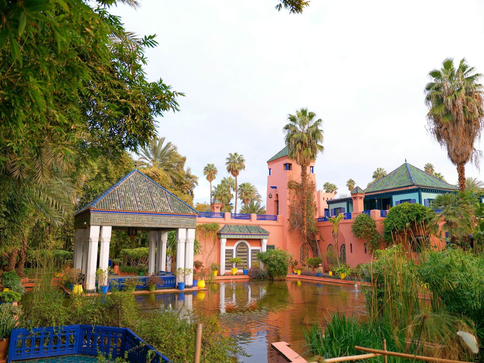 Pink buildings and palm trees surround a tranquil garden pond.