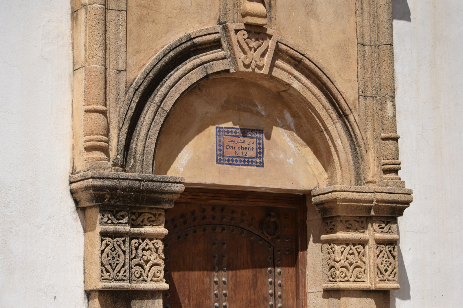 Ornate archway above a wooden door with decorative tiles.