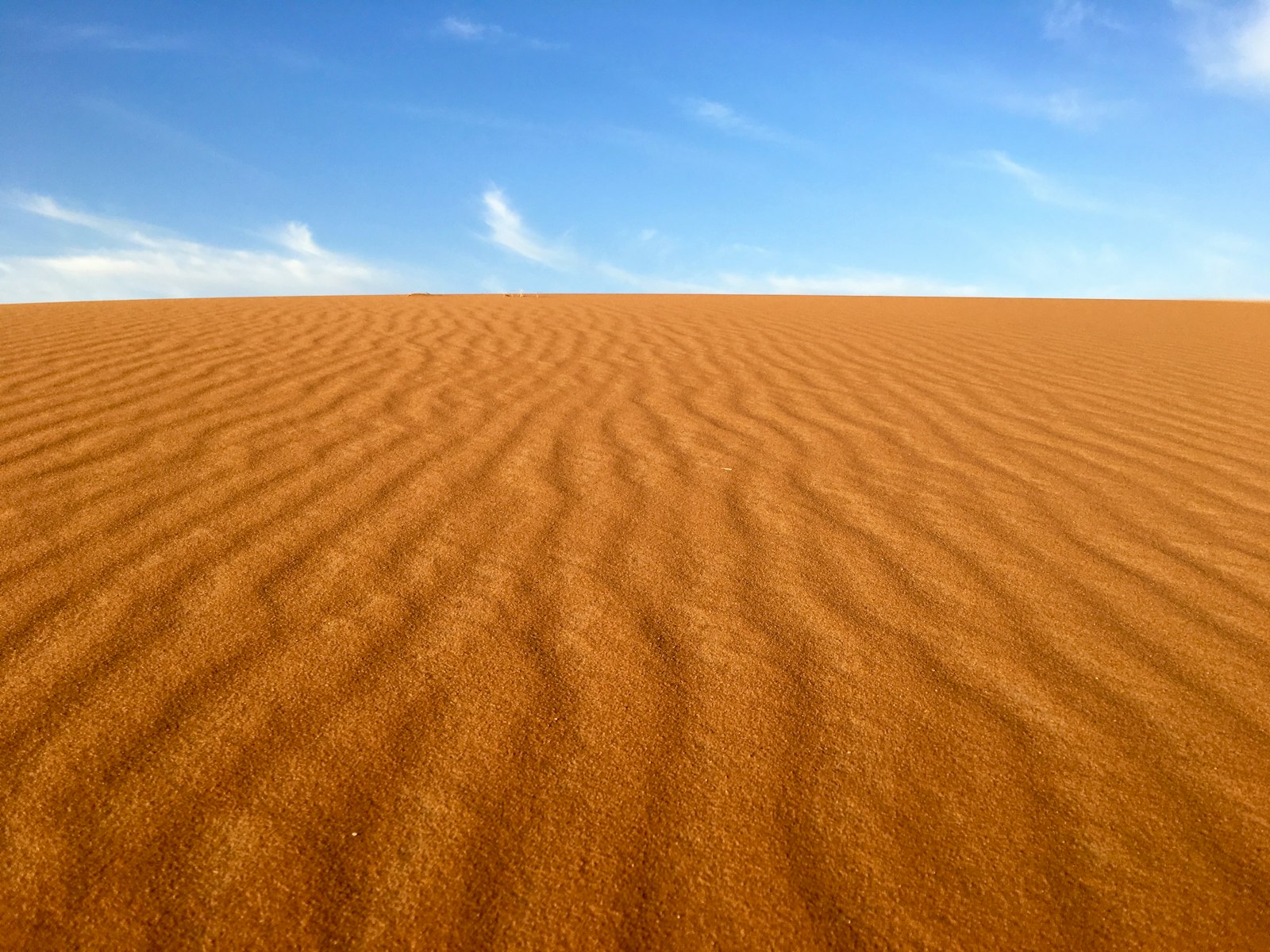 brown sand under blue and white sky