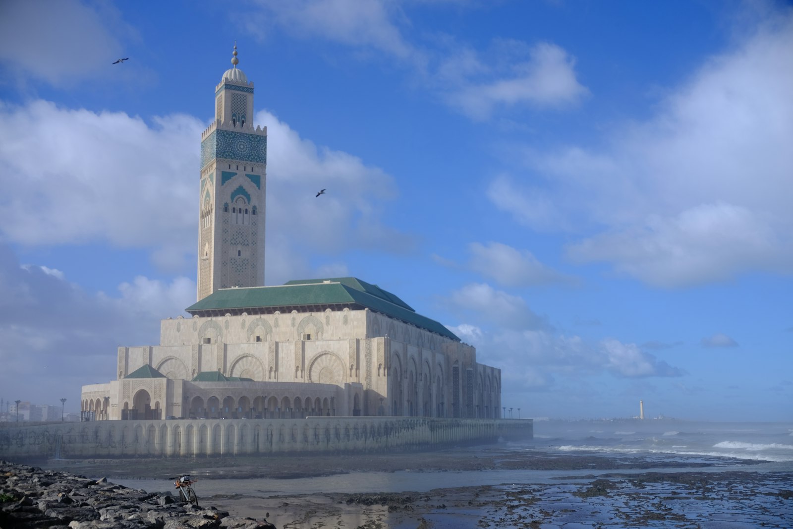 The grand hassan ii mosque stands majestically by the ocean.