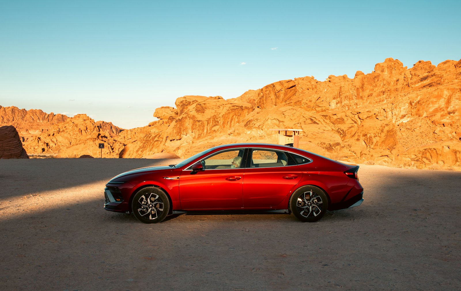 A red car is parked in a desert landscape.