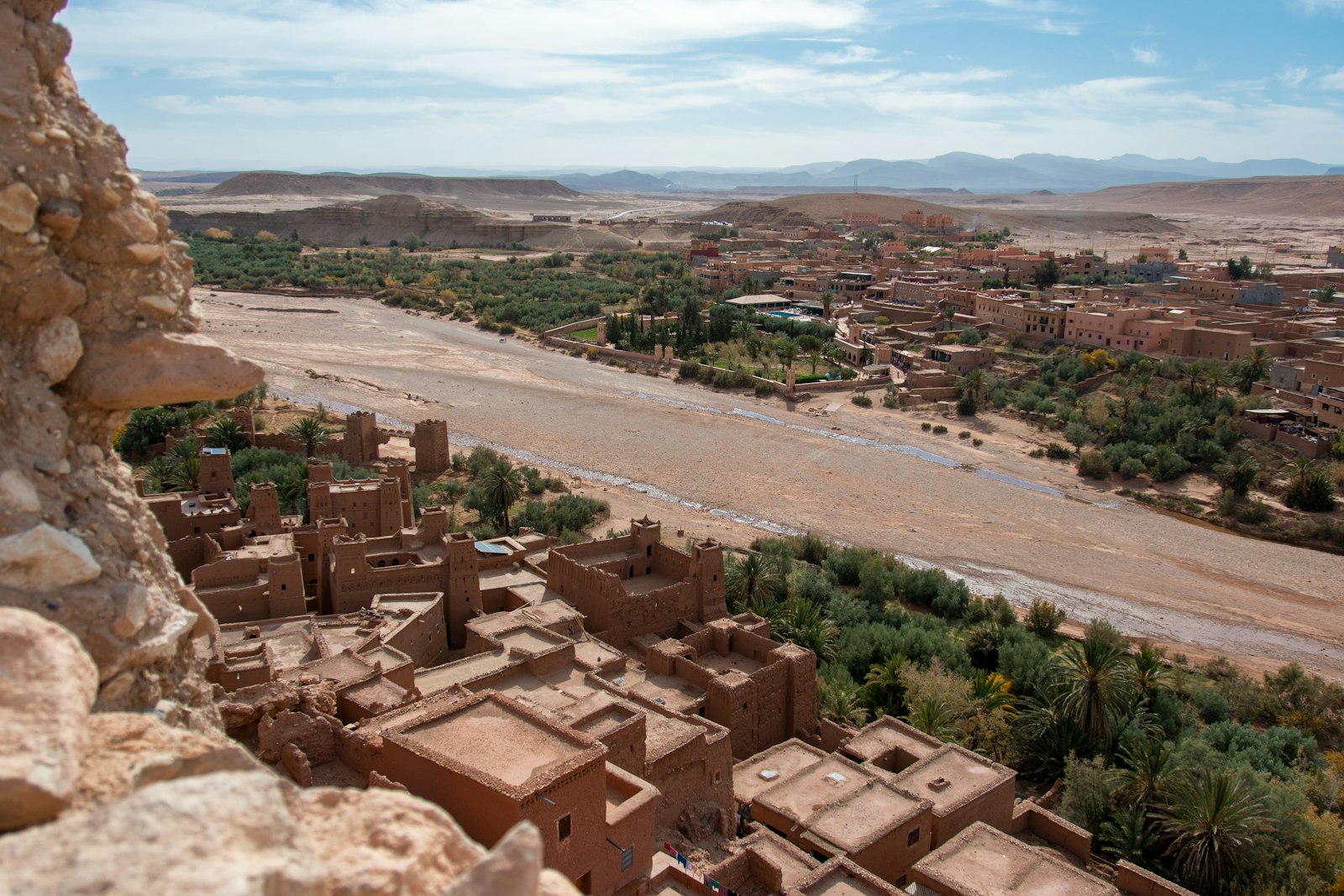 Ancient moroccan village with a river and distant mountains.