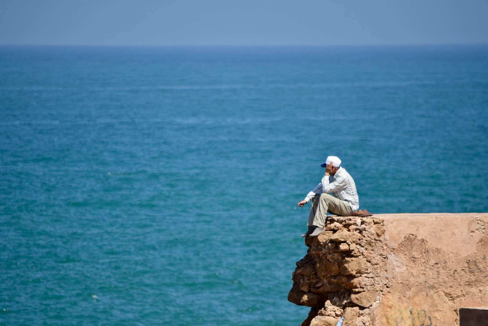 Man sitting on cliff edge overlooking the ocean