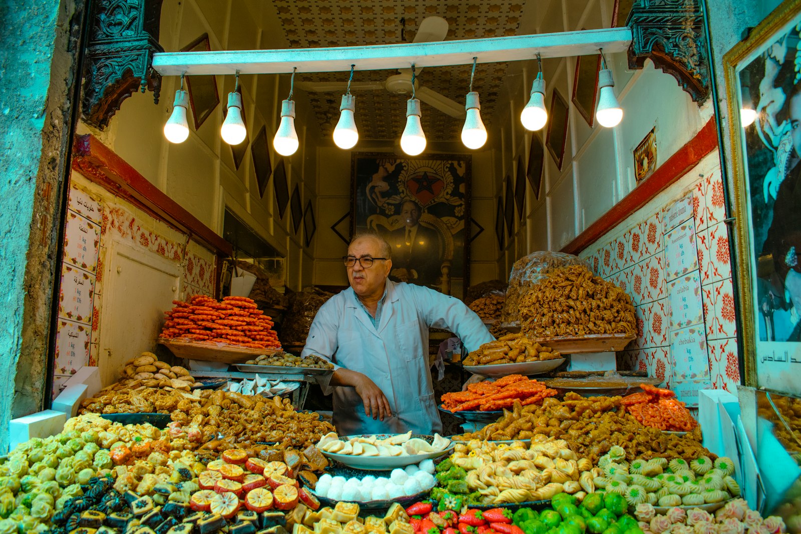 A man stands behind a counter of colorful treats.