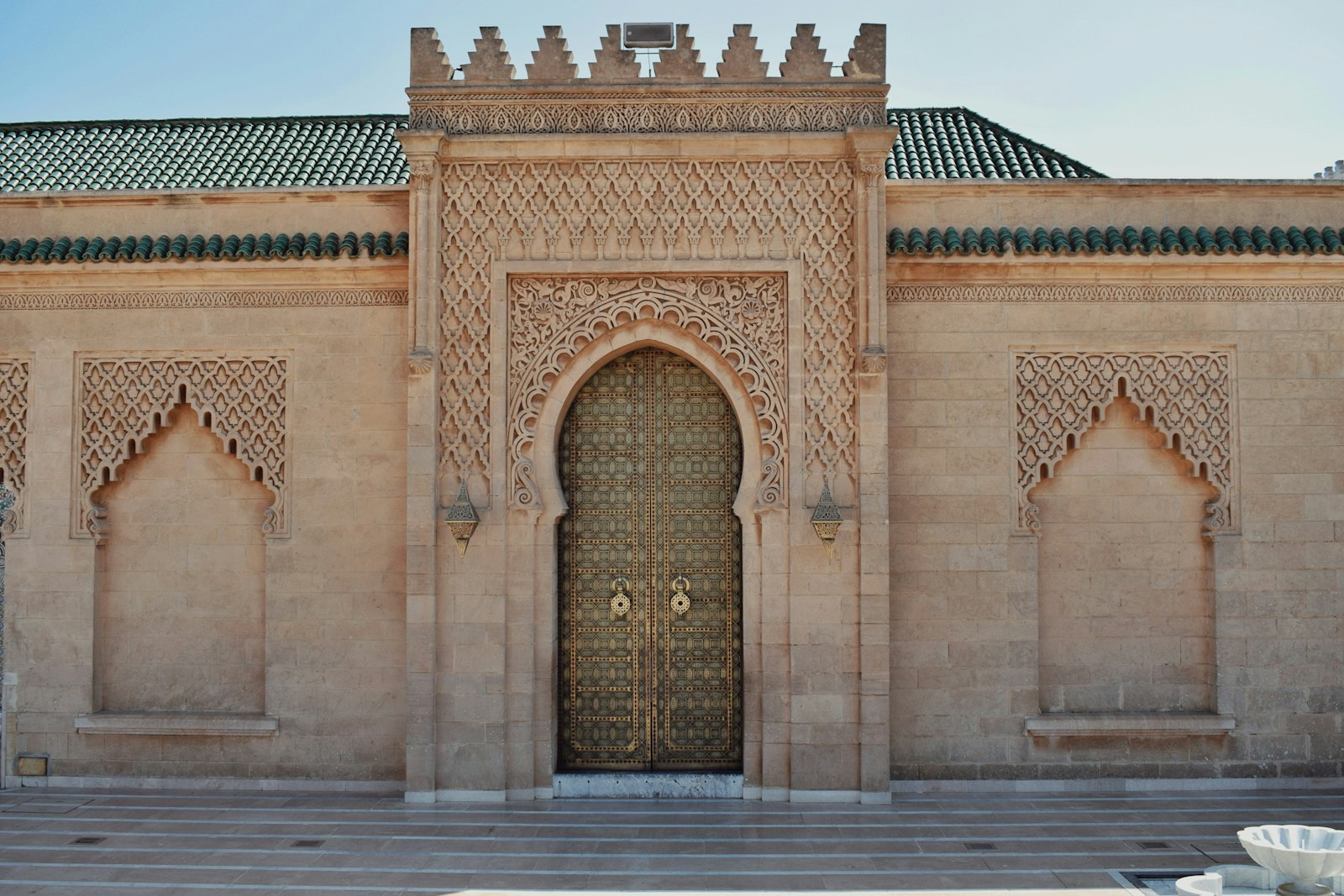 Ornate golden door on a sand-colored building
